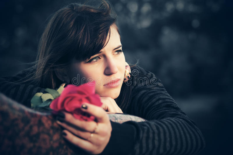 mujer-joven-triste-con-una-rosa-roja-82211909